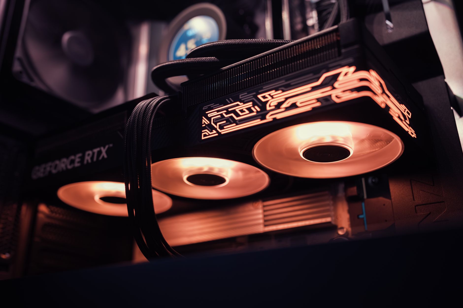 Gros plan d’une carte graphique GeForce RTX avec deux ventilateurs et un éclairage orangé, installée dans un boîtier d’ordinateur.